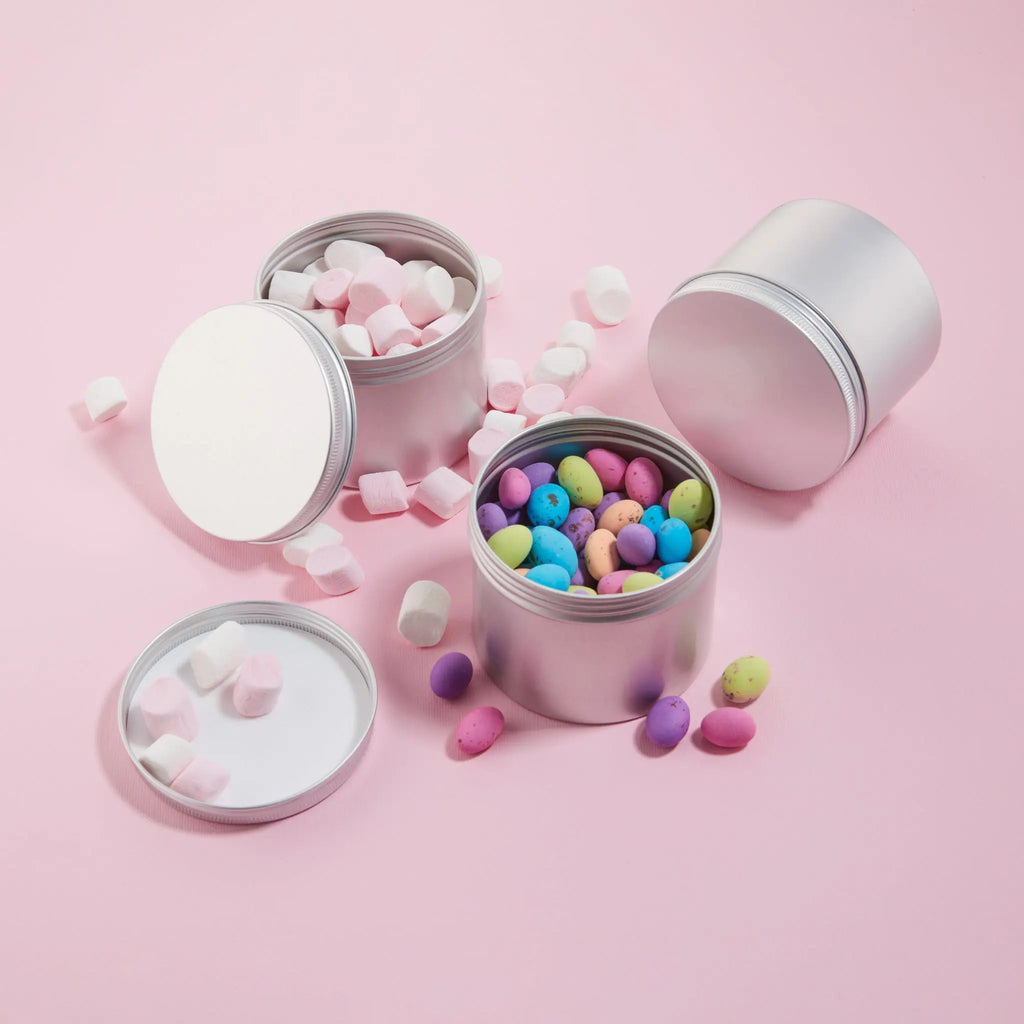 Reusable tins. Silver tins filled with colorful candies on a pink background