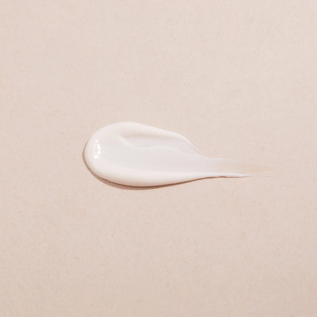 White cream smear on a beige background showing consistency of ENOUGH Vinifirm Countouring Crème