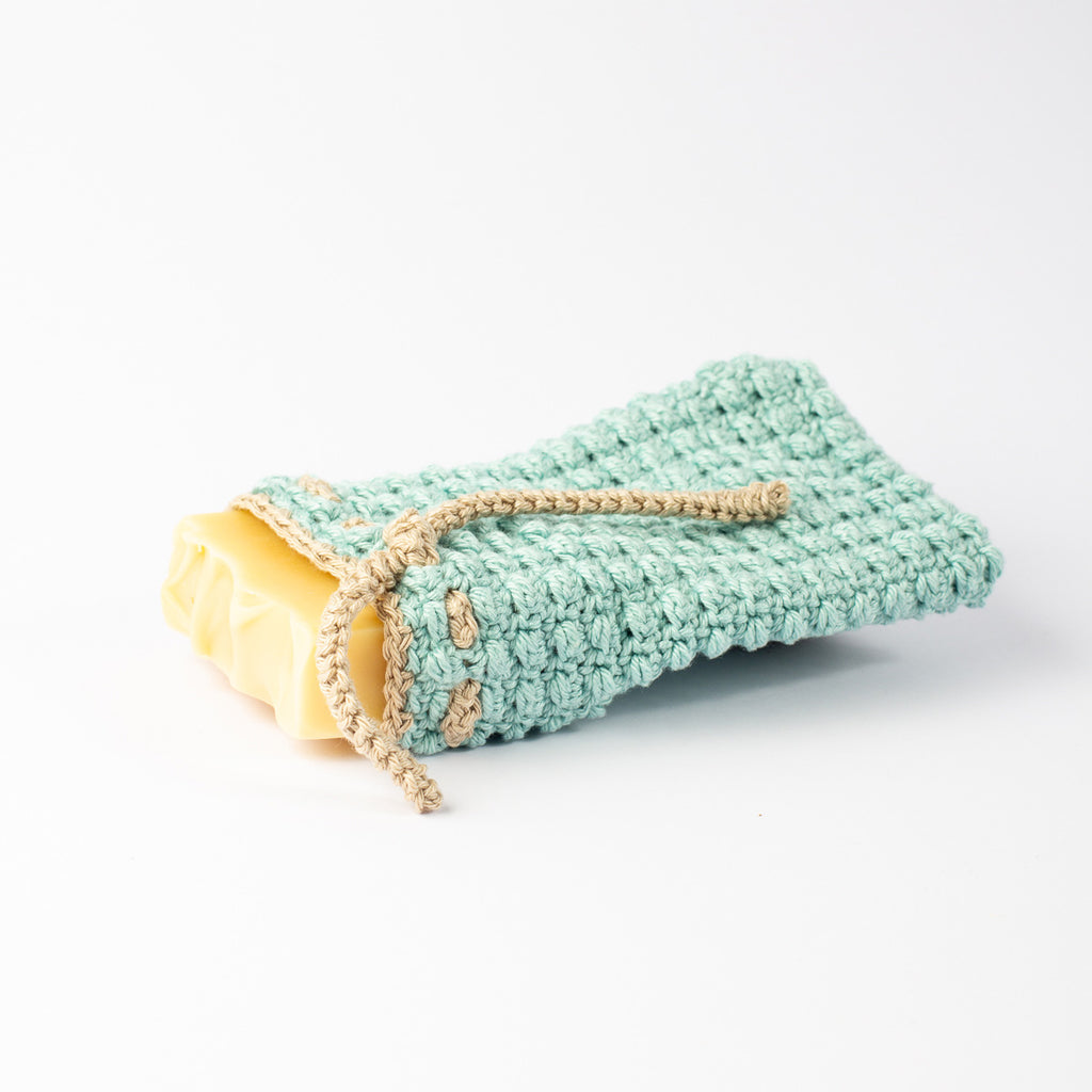 CONIQUE natural cotton soap saver bag in use with bar soap inserted, drawstring loosened, side view
