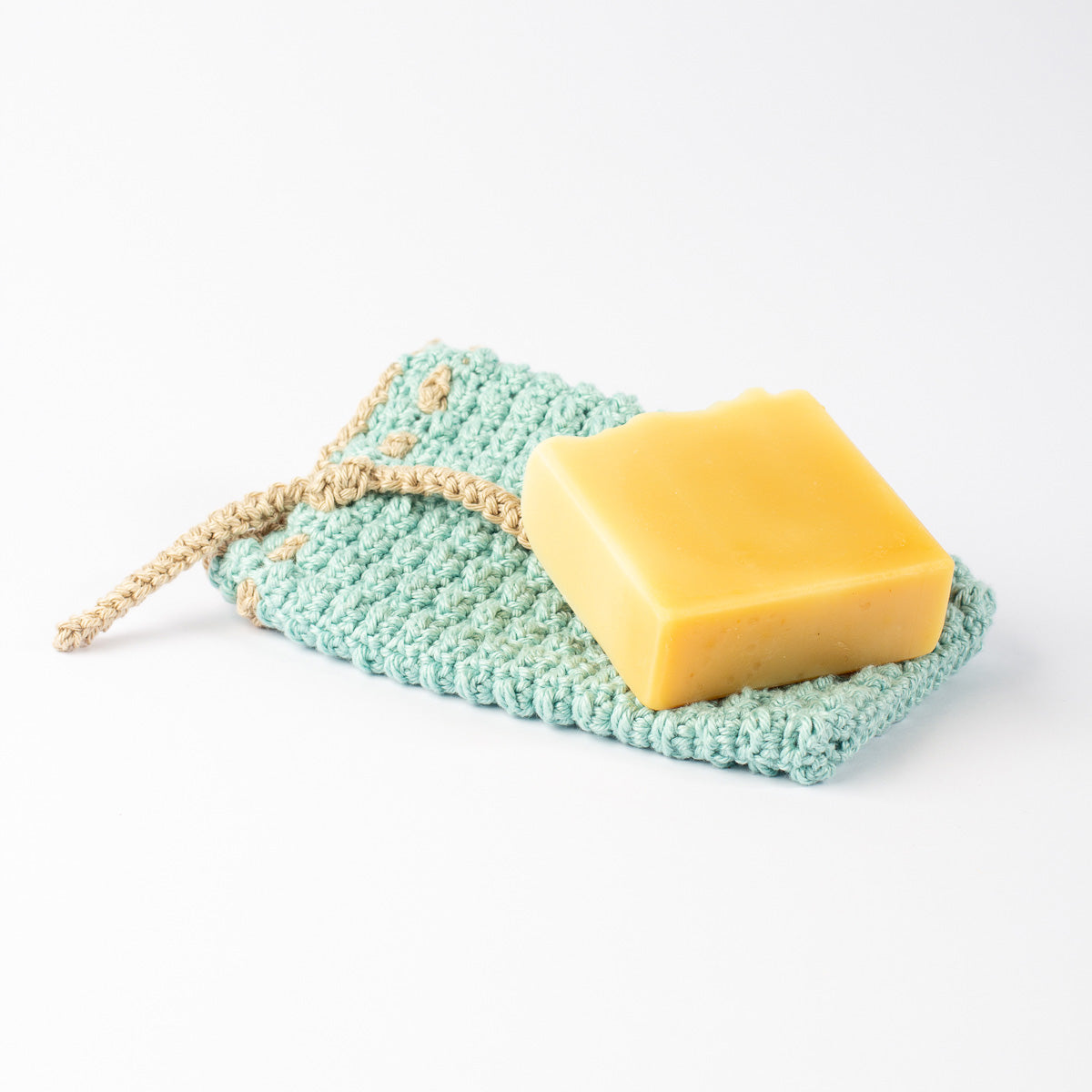 ECONIQUE cotton soap saver bag open flat with golden natural bar soap resting on top, white background