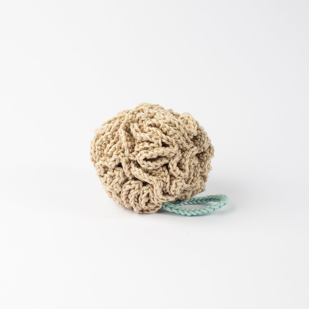 Side-angle view of ECONIQUE natural cotton shower sponge in beige showing textured crochet detail and sage loop.